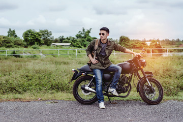 Fototapeta premium Rowerzysta na motocyklu nad naturalnym jeziorem i piękny, cieszący się wolnością i aktywnym stylem życia, bawiąc się na wycieczce motocyklowej. Tło zachodu słońca i niebo.