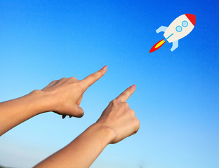 Female hands point to the rocket