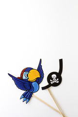 Paper props for holidays and parties on a white background. Parrot and bandage of a pirate