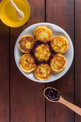 Cottage cheese pancakes on a wooden background. Traditional Ukrainian dish - syrniki with jam and honey. Pancakes with cottage cheese on a white plate. Copy space