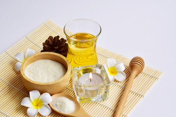 Homemade spa set which consists of body and facial scrub, hair treatment oil, aroma candle and flowers in oriental style on white background, body and hair care concept