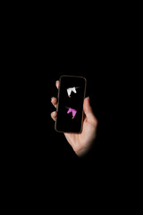 Unicorns - A hand, a black phone on a black background © dmytrobandak