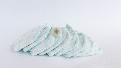 Baby diapers on a white background and a flower dandelion