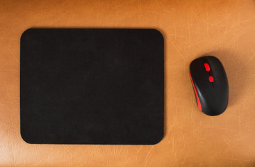 Computer mat and computer mouse on a brown leather background, close-up, modern