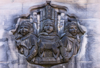 Edinburgh, Scotland, UK - June 13, 2012; Closeup of stone mural featuring three singing choir boys with organ pipes behind them. Partly blackened in beige side stone wall of Parliament House.