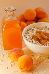 Healthy breakfast. White plate of oatmeal with dried apricots, a glass of an apricot juice and fresh apricots on a white table.