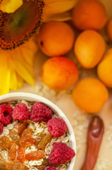 Healthy breakfast. White plate of oatmeal with dried apricots and raspberries, a glass of an apricot juice and fresh apricots on a white table.
