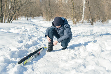 Boy teenager on skis in a park of winter snow drifts