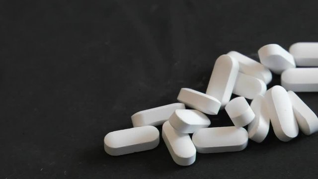 White pills (magnesium) on a black background