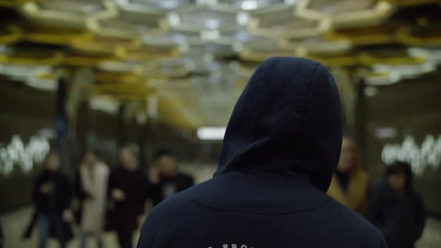 Rear view of a single hooded man in the subway. Concept of loneliness