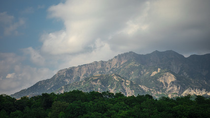 Majestic landscape of the mountains and forest in Caucasus at summer. Dramatic sky with clouds.