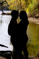 Silhouette couple by river’s edge