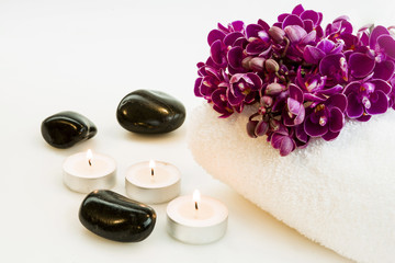 Bouquet of orchid on a white towel, candles and stones isolated on a white background