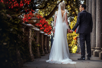 Lovely couple of newlyweds - bride and groom walking around a old beautiful stone palace outdoors.