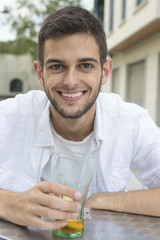 smiling young man in the open air cafeteria with drink