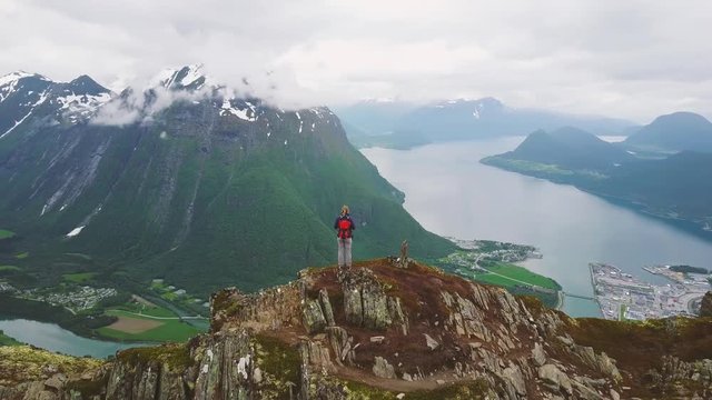 turning around hiker standing on top of mountain in Norway, travel to fjords, aerial landscape