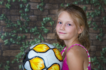 The girl is holding a soccer ball and looking into the camera. - Powered by Adobe