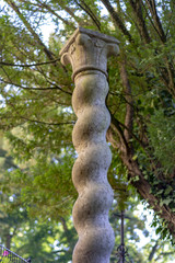 The twisted column in the garden. Decorative element isolated with clippeing path on natural background.