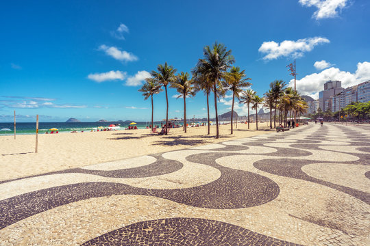Copacabana Beach with palms and famous mosaic sidewalk in Rio de Janeiro, Brazil.