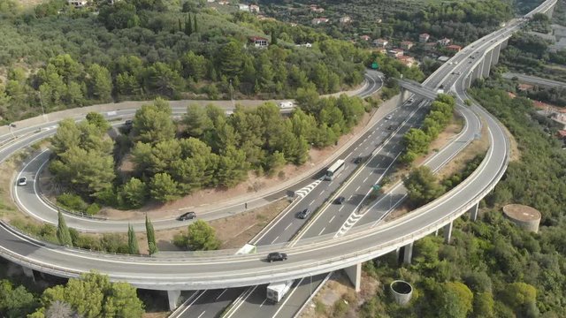 Aerial: flying near multiple lane highway crossing villages and forest hills (Autostrada dei Fiori - A10) Liguria Italy. Native Cinelike D-Log ungraded flat color profile.