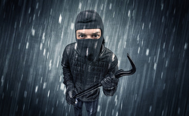 Burglar in action in black clothes with rainy concept. 
