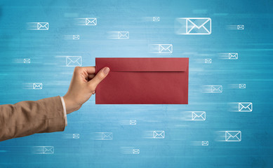 Female hand holding coloured and white envelope with blue background and message symbols around
