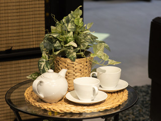 A beautiful white set of two bowls and a teapot, in the background a flower