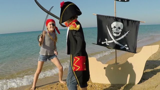 Two happy little children playing on the beach at the day time. They are dressed in sailor's vests. Kids having fun outdoors. Concept of sailors on vacation. 