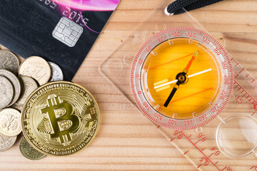 Gold physical Bitcoin with coins, credit card and a compass.
