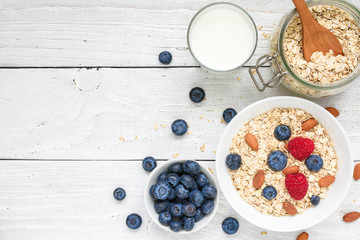 Healthy breakfast ingredients. homemade oats with raspberries and blueberries, milk and nuts for muesli