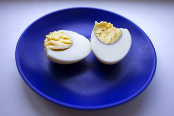 boiled egg on a blue saucer. Dietary nutrition.
