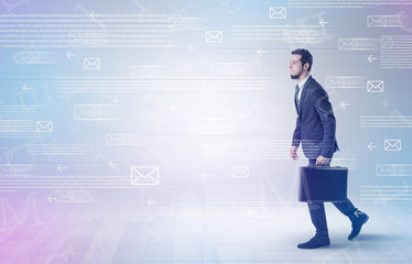 Handsome businessman walking in suit with briefcase on his hand and online communication concept around
