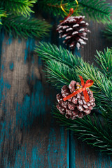 Fir branches with cones on wooden rustic desk. Christmas decoration. Space for text.