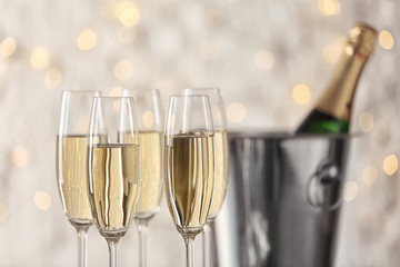 Glasses with champagne and bottle in bucket against blurred lights