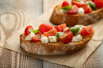 Bruschetta with tomatoes, mozzarella cheese and basil on a old rustic table. Traditional italian appetizer or snack, antipasto. with copy space