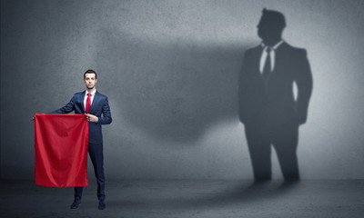 Businessman standing with red cloth on his hand and his shadow on the background
