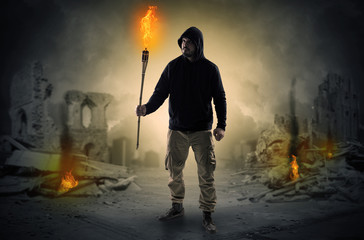 Obraz premium Destroyed place after a catastrophe with man and burning flambeau concept 