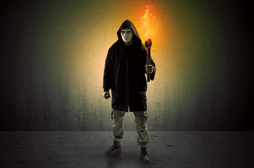 Ugly scary man with burning flambeau walking in an empty space