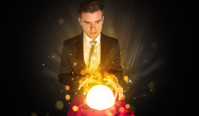 Gorgeous businessman sitting with sparkling magic ball in his lap
