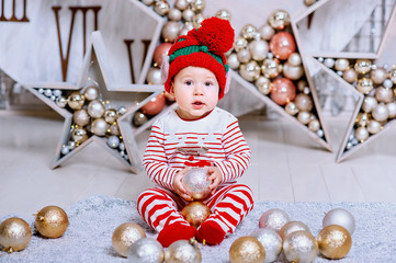 Little boy in elf hat waiting for a Christmas holding tree decoration.