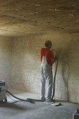 young man grinds wall in basement cellar for renovate 