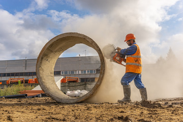 Worker at the construction site cuts the ring for the well with concrete cutters