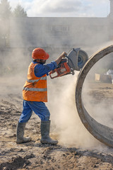 Worker at the construction site cuts the ring for the well with concrete cutters
