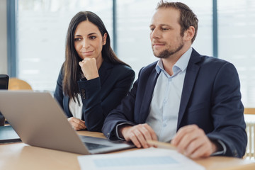 manager sitzen am tisch und schauen gemeinsam auf ein notebook