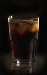 Glass still life image Cola with ice in a glass on a black background