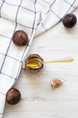 Glass jar of fig jam and fresh figs on white wooden background, top view. From above, overhead.