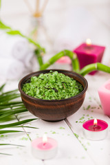 Spa. Green herbal spirulina salt in ceramic bowl, spa towels, pink scented candle and bamboo