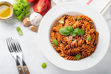 Fusilli pasta with tomato sauce, garlic, Basil and Parmesan cheese on white background. Top view. Flat lay