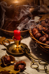 Autumn still life with a candle, chestnuts and an old copper coffeepot