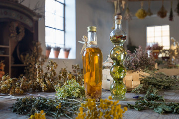 Two bottles with oil on a table with dried herbs and flowers